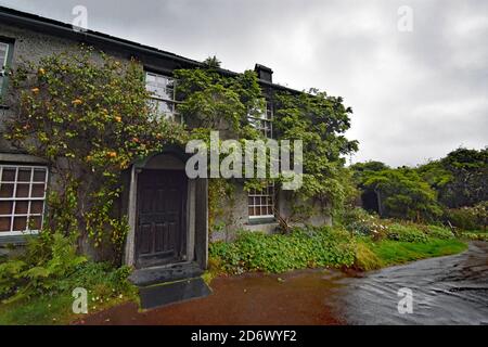 Hill Top, home of children's author, Beatrix Potter, in the Lake District, England. Main entrance to the cottage and an apple tree climbs up the wall. Stock Photo