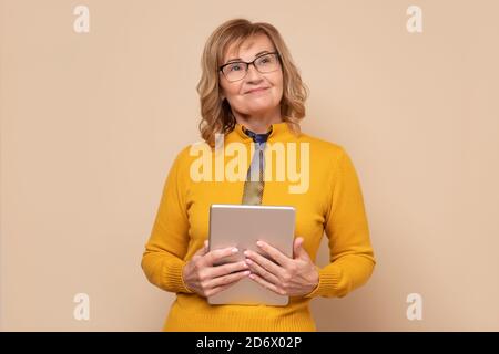 Mature woman in glasses holding tablet computer working on touching screen. Stock Photo