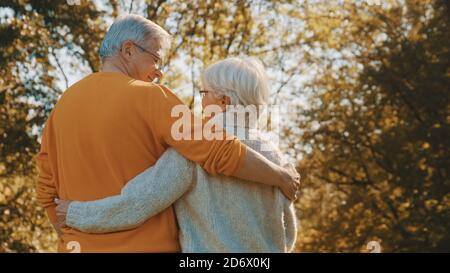 Happy old couple hugging in park. Senior man flirting with elderly woman. Romance at old age on autumn day. High quality photo Stock Photo