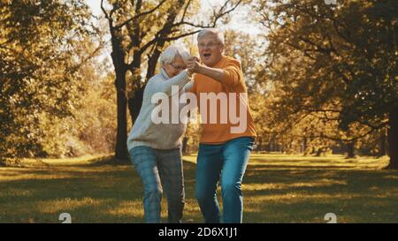 Happy old couple dancing in park. Senior man flirting with elderly woman. Romance at old age autumn day. High quality photo Stock Photo