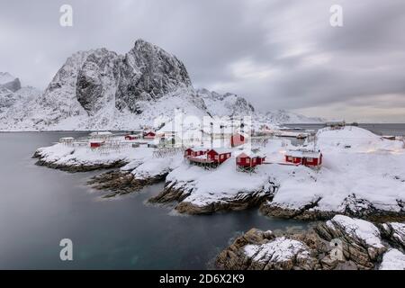 Landscape of the Lofoten Islands in Norway with traditional wooden red fisherman huts in front of the sea and this beautiful moutain in the background Stock Photo