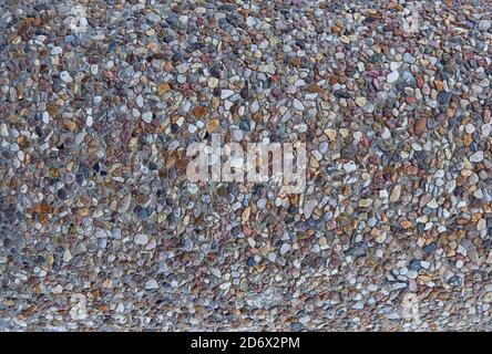 texture of stones in a light-colored concrete fence, crushed stone. Stock Photo