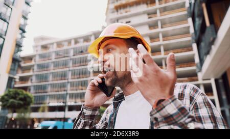 Engineer talking on phone. Architect using phone on construction site. Foreman phone call control process. Construction worker communications in Stock Photo