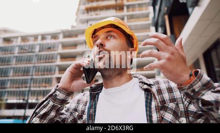 Engineer talking on phone. Architect using phone on construction site. Foreman phone call control process. Construction worker communications in Stock Photo