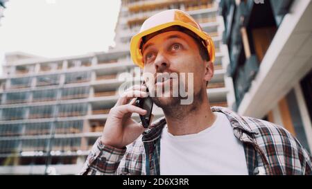 Engineer talking on phone. Architect using phone on construction site. Foreman phone call control process. Construction worker communications in Stock Photo