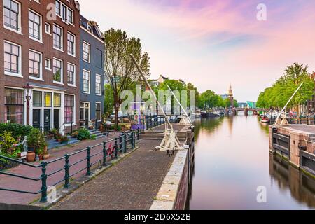 Amsterdam streets and canals during dusk, summer season. Sint Antoniesluis, popular travel destination for tourists. Stock Photo