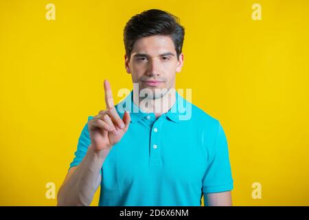 Man disapproving with no sign make negation finger gesture. Denying, Rejecting, Disagree, Portrait of guy on yellow background. Stock Photo