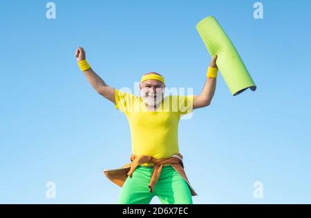 Funny Senior man Jumping. Old man jumping on blue sky background. Freedom retirement concept. Fit senior man resting after working out. Stock Photo