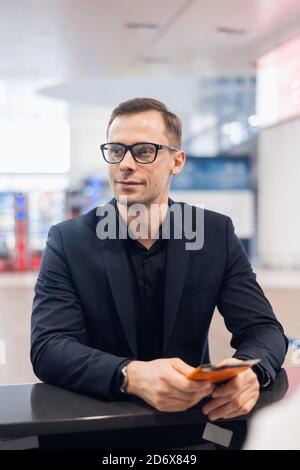 Handsome businessman handing over air ticket at airline check in counter Stock Photo