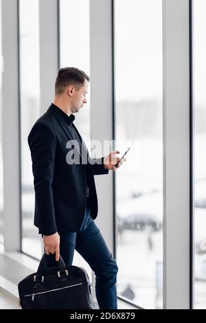 Business man using mobile phone app in airport. Young business professional man texting smartphone walking inside office building or airport terminal Stock Photo