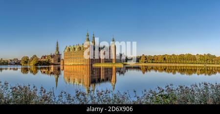 Panoramic view of Frederiksborg Castle in a mirror-gloss reflection in the lake at surise, Hillerød, Denmark, October 17, 2020 Stock Photo
