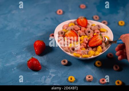 Healthy breakfast with cereal and berries. From above of bowl with delicious healthy breakfast made with colorful cereal rings and fresh strawberry Stock Photo