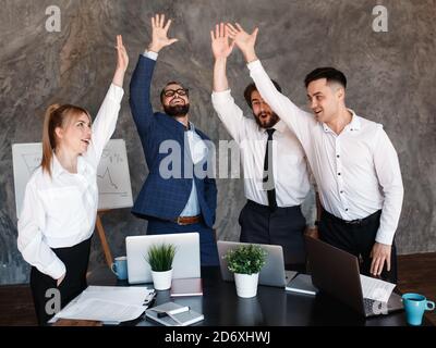 Excited multiracial office associates employees group giving high five engaged in coaching team spirit, motivated by unity, involved in good corporate Stock Photo