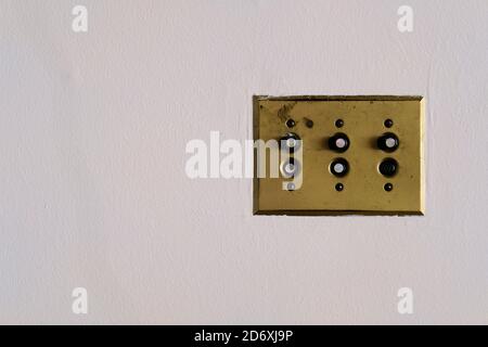 H&H Arrow single pole push light switches mounted on a brass plate on a white wall; manufactured in the 1930s by Arrow-Hart & Hegeman Electric Co. Stock Photo