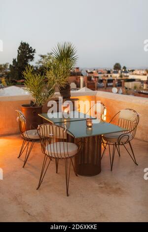 Table for romantic dinner on rooftop terrace in evening. Moroccan style, vintage lamps, candles, cactus flower, twilight. Stock Photo