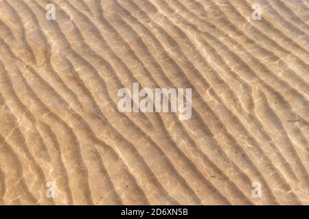 Sandy seabed wavy pattern under shallow water Stock Photo
