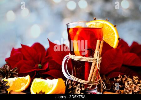 Christmas drink. Glasses of hot mulled wine with oranges, anise and cinnamon next to the red poinsettia flower. Stock Photo