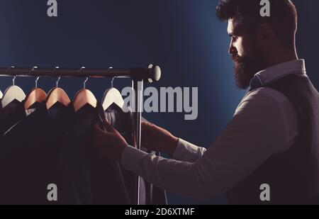 Tailor, tailoring. Men's suit, tailor in his workshop. Elegant man's suits hanging in a row. Luxury mens classic suits on rack in elegant men's Stock Photo