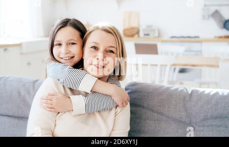 daughter hugs mom and looks at the camera Stock Photo