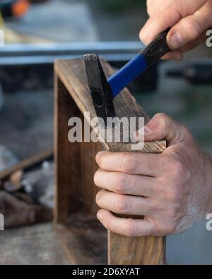 Man using hammer and nail on wood, close up Stock Photo