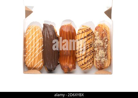 Set eclairs with different flavors and fillings in box on white background. Top view Stock Photo