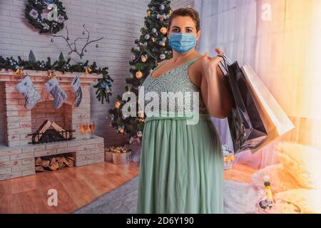 An overweight, elegant woman with a mask and bells in her hand rings the bell for the presents in Covid 19 times. Stock Photo