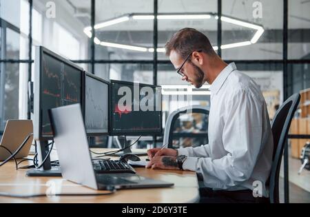 Male stockbroker in formal clothes works in the office with financial market Stock Photo