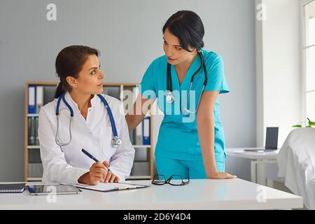 Doctor and her assistant working together at hospital. Physician and nurse with documents at medical office Stock Photo