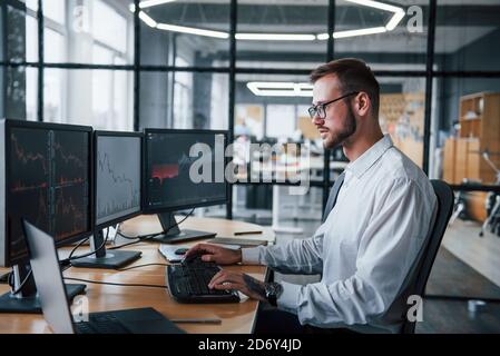 Male stockbroker in formal clothes works in the office with financial market Stock Photo