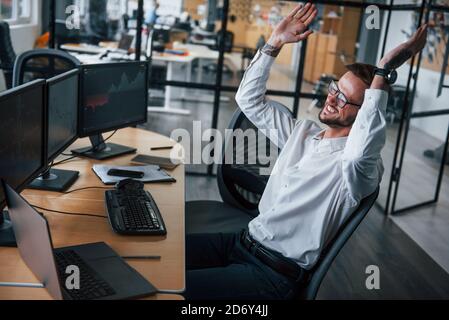 This is success. Male stockbroker in formal clothes works in the office with financial market Stock Photo