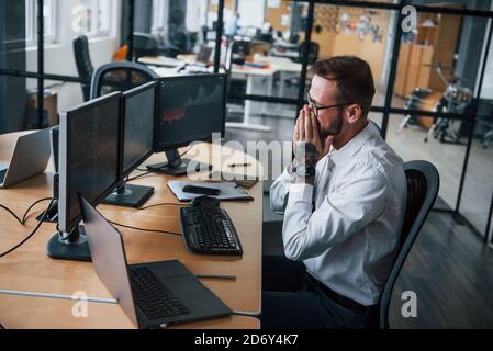 Worried facial expression. Male stockbroker in formal clothes works in the office with financial market Stock Photo