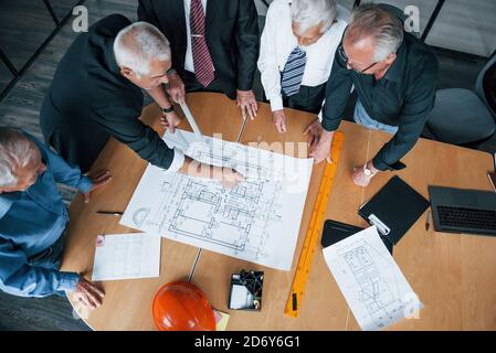 Top view of aged team of elderly businessman architects have a meeting in the office and works with plan Stock Photo