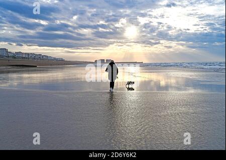 Brighton UK 20th October 2020 - Walkers on Brighton beach enjoy the breezy but bright morning at low tide . Wet and windy conditions are forecast for the next few days throughout Britain as Storm Barbara approaches from Europe : Credit Simon Dack / Alamy Live News Stock Photo