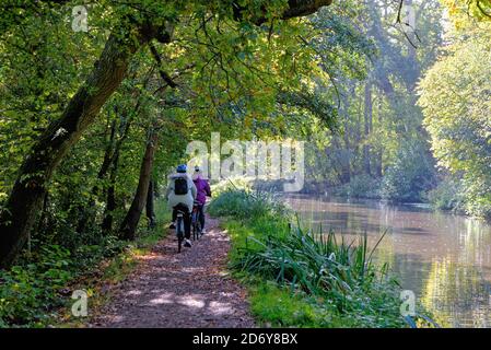 Two cyclists on the towpath of the River Wey Navigation canal on a sunny autumnal day, Byfleet Surrey England UK Stock Photo