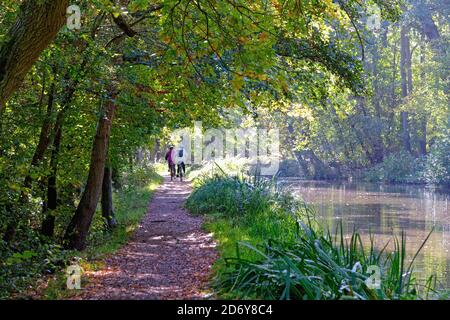 Two cyclists on the towpath of the River Wey Navigation canal on a sunny autumnal day, Byfleet Surrey England UK Stock Photo