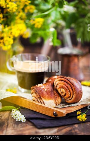 Homemade cinnamon and cardamom rolls (buns) and cup of black coffee Stock Photo