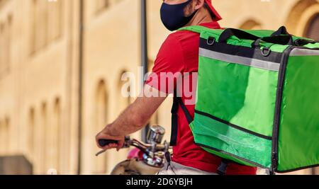 Courier with refrigerator bag on scooter wearing protective face mask during work at qurantine, cropped. Food delivery concept Stock Photo