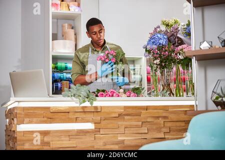 Young florist working in shop with laptop Stock Photo