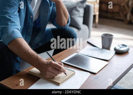 Man in casual clothes working with financial documents while sitting on sofa at home. Stock Photo