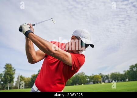 Male golfer doing a golf swing outdoors Stock Photo