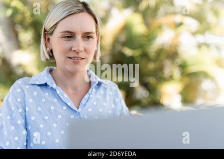 Young business woman working at the laptop outdoors. Happy smile. Stock Photo