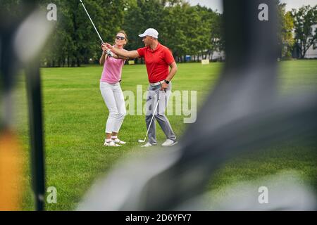 Smiling female beginner taking a golf lesson from a professional Stock Photo