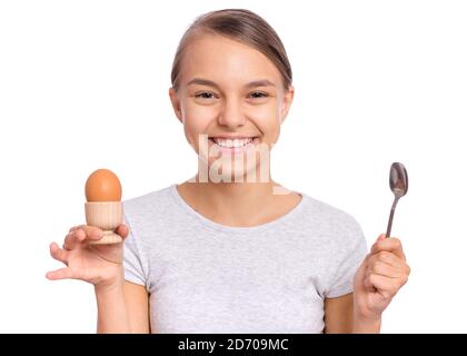Portrait of beautiful young teen girl, holding boiled egg and spoon for breakfast, isolated on white background Stock Photo