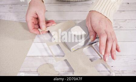 Step by step. Cutting out gift tags from brown paper with a paper punch. Stock Photo