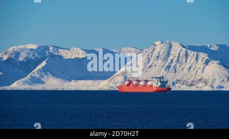 Big red painted LNG (liquefied natural gas) carrier vessel lying at anchor in the arctic ocean in front of Sørøya island in winter time. Stock Photo