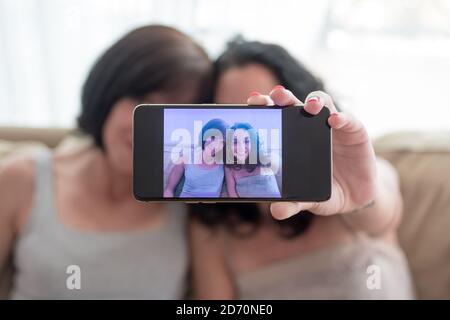 two young women have fun and laugh while taking a selfie with their phones Stock Photo