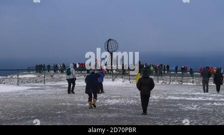 Nordkapp, Norway - 02/28/2019: Tourists from a Hurtigruten cruise ship on a day tour to North Cape gathering around popular globe sculpture in winter. Stock Photo