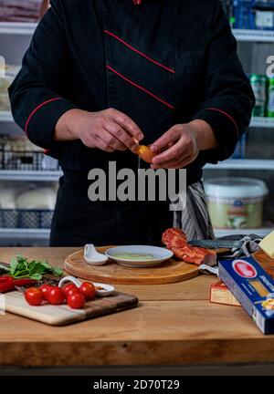 The cook breaks the egg and separates the egg white from the yolk. Stock Photo