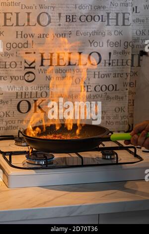 Chef cooking with flame in a frying pan on a kitchen stove Stock Photo