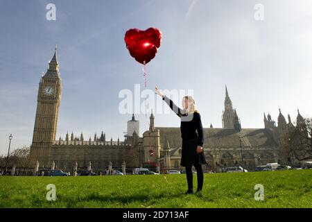 A girl takes part in a global recreation of Banksy's â€œGirl with Red Balloonâ€, to mark 3rd Anniversary of Syria Crisis, in Parliament Square, London. Stock Photo